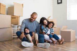 Family smiling in the middle of moving boxes in their new home